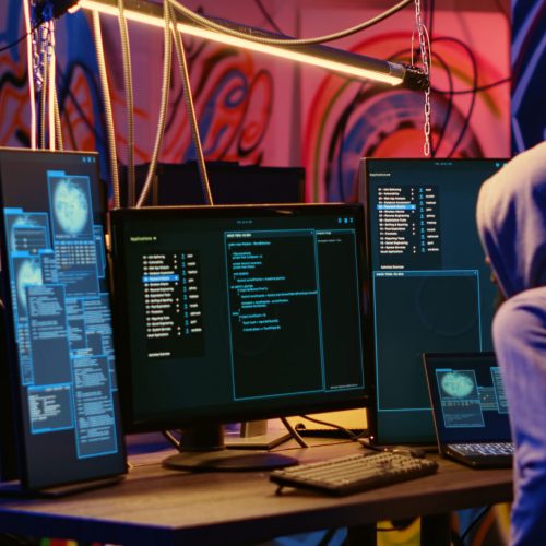 Malicious computer specialists in secret abandoned warehouse working together to get past anti tamper measures implemented by companies to protect their software, uploading crack to torrent websites